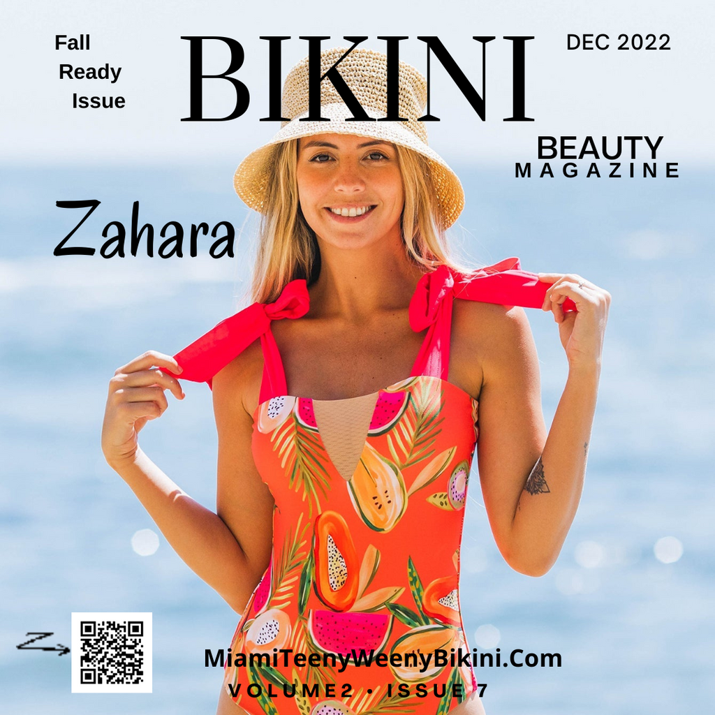 Woman in tropical print one-piece swimsuit and straw hat posing on the beach, magazine cover style