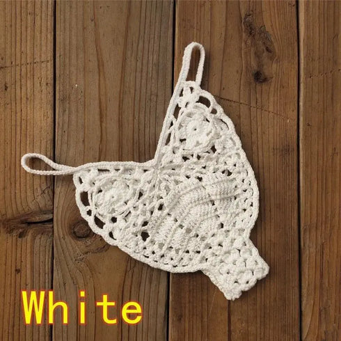 White crochet bikini thong bottom on wooden background, women's swimwear.