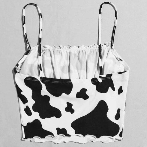 Black and white cow print bikini top with spaghetti straps on a plain background