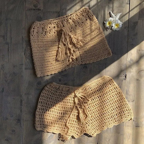 Beige crochet knit bikini cover up skirts with tassel ties, laid on wooden surface
