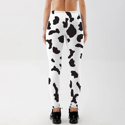 Woman wearing high-waisted cow print leggings, back view, in a minimal studio setting