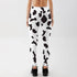 Woman wearing high-waisted cow print leggings, back view, in a minimal studio setting
