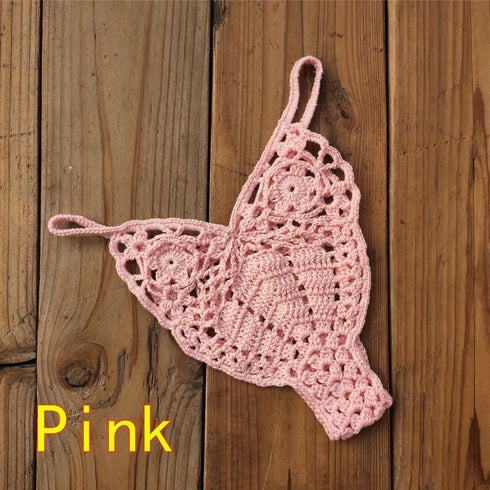 Pink crochet bikini thong bottom on wooden background, women's swimwear