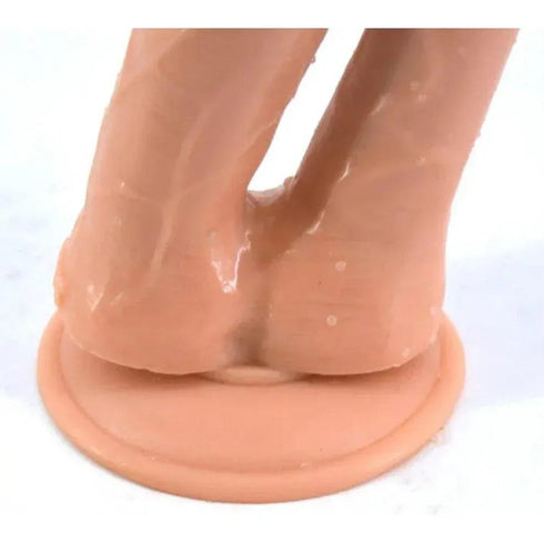 Close-up of a realistic silicone novelty product with a round base on a white surface.