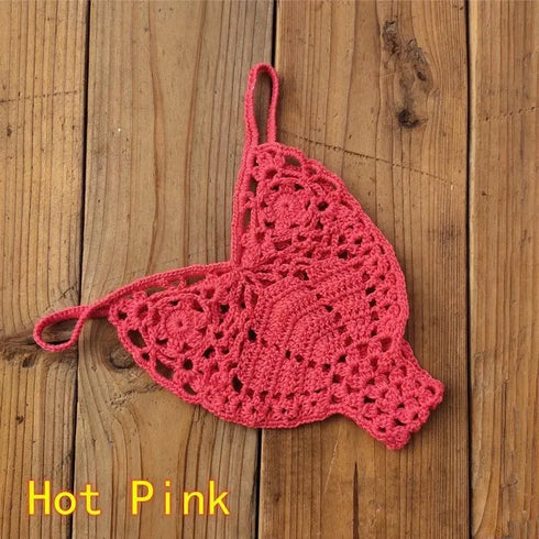 Hot pink crochet bikini thong bottom on wooden surface, trendy swimwear fashion.