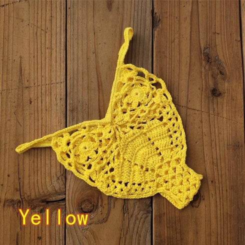 Yellow crochet bikini top with floral pattern on rustic wooden background