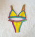 Yellow crochet bikini set with colorful trim on white textured background