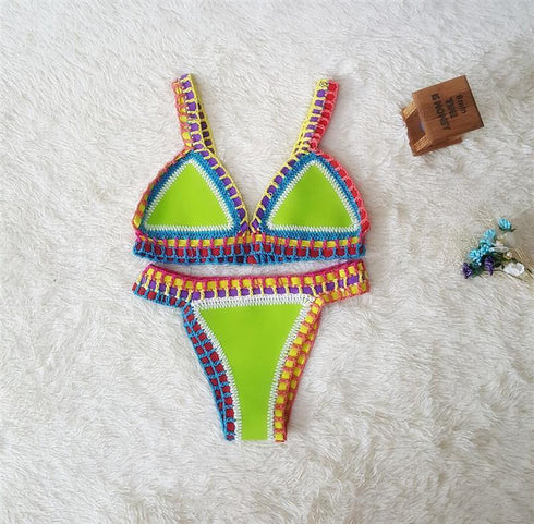 Neon green crochet bikini set with colorful trim, displayed on soft white fabric.