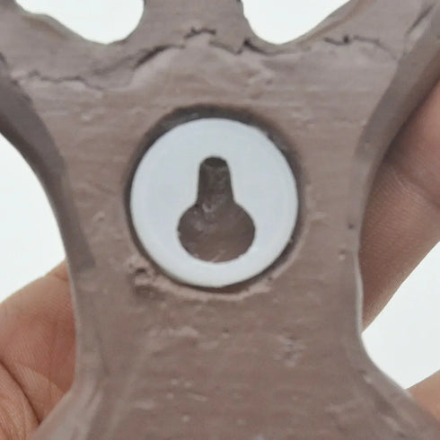 Close-up of a metallic gear with a central hole, held by a hand against a white background.