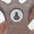 Close-up of a metallic gear with a central hole, held by a hand against a white background.