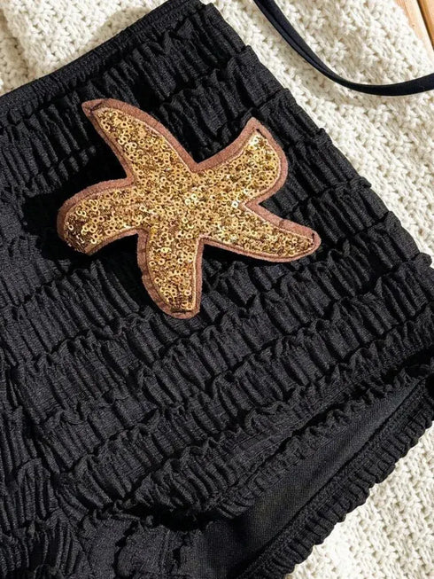 Black textured bag with a gold starfish patch on a light background