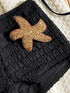 Black textured bag with a gold starfish patch on a light background