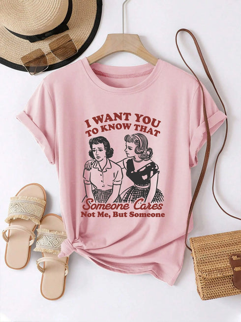 Pink t-shirt with graphic design and text, surrounded by a hat, sandals, and bag on a white background