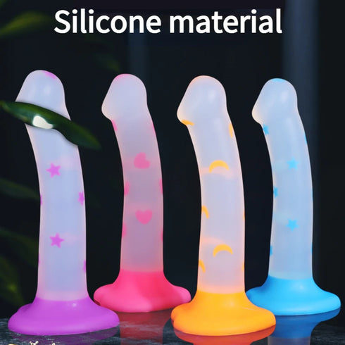 Four silicone toys in different colors with star, heart, and circle patterns on a dark background.